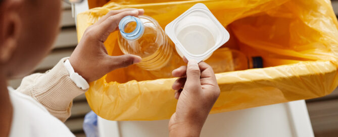 Person placing plastic bottle and pot into bin.